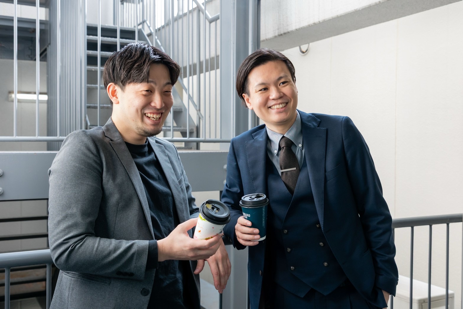 コーヒーを片手に笑い合うBLAYNの社員2名